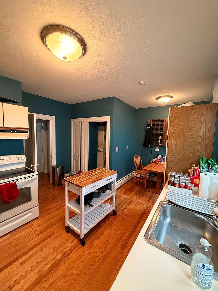 Living room with a brick fireplace and hardwood floors in Unit 1 on Ardmore Rd.